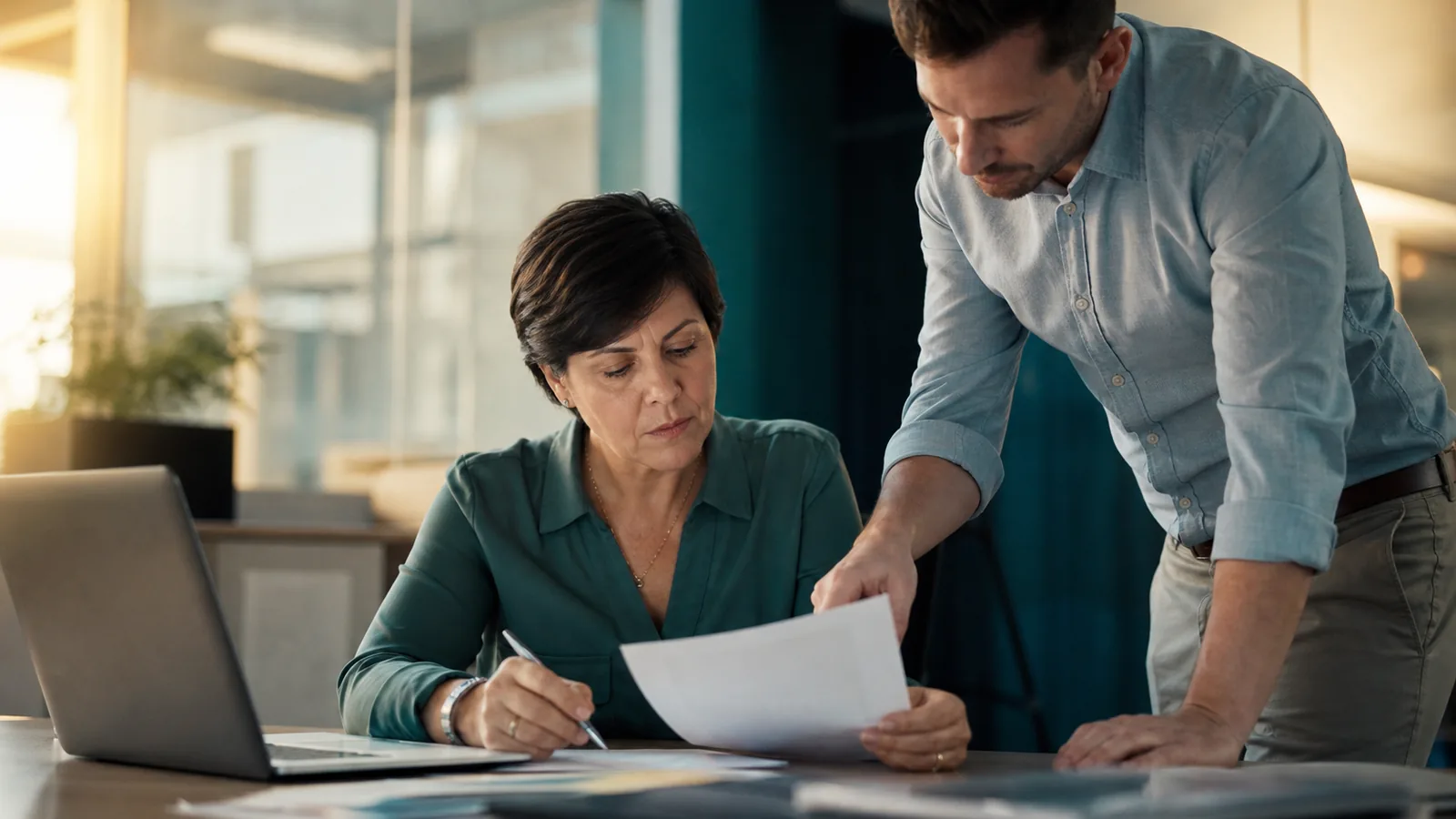 IT service manager reviewing a vendor contract renewal at her desk with a colleague